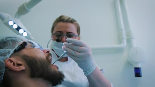 牙医在办公室工作。一位女医生检查男性病人的牙齿和下巴.. — 图库视频影像