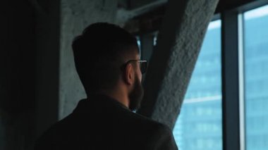 Genç başarılı iş adamı şehir pencereden dışarı bakıyor. Yüksek işletme binası. Office loft tarzı