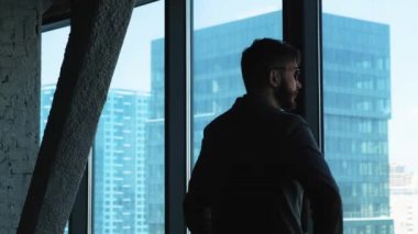 Genç başarılı iş adamı şehir pencereden dışarı bakıyor. Yüksek işletme binası. Office loft tarzı