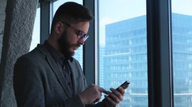 İş başarısı ve başarısı. Mutlu iş adamı cep telefonuyla kutlama yapıyor. Genç şehirli profesyonel başarılı iş adamı kişisel hedeflerine ulaşıyor. Akıllı telefon uygulaması veya video oyunu konsepti.