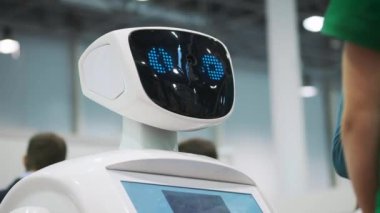 Beyaz bir robot yeni teknolojilerin bir sergi, bir öğrenci ile etkileşim kurar. Çocuk yenilikleri ile tanışması