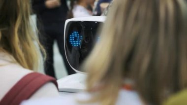 Beyaz bir robot yeni teknolojilerin bir sergi, bir öğrenci ile etkileşim kurar. Çocuk yenilikleri ile tanışması