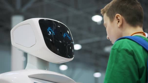 Μόσχα - Ρωσία, 20.03.2018: ένα λευκό ρομπότ αλληλεπιδρά με μαθητής σε μια έκθεση των νέων τεχνολογιών. Το παιδί γίνεται εξοικειωμένο με καινοτομίες — Αρχείο Βίντεο