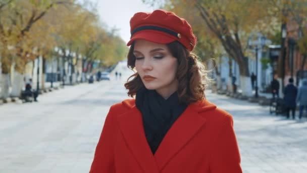 Retrato: Joven modelo adolescente elegante posando para una sesión de fotos en la ciudad de otoño. Vestido con abrigo rojo. Mirada de película — Vídeo de stock