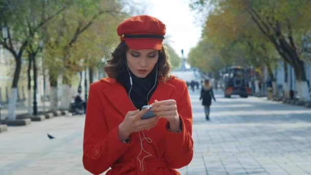 Elegantes junges Mädchen in rotem Mantel tanzt frei auf der Straße. Es macht Freude. — Stockvideo