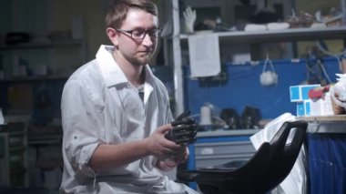 Bir mühendis elektronik biyonik protez kolu test ediyor. Mekanik bir kolun plastik parmaklarını hareket ettiriyor. Protezde modern teknolojiler. Bir bilim adamının elinde sibernetik bir el