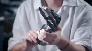 Bir mühendis elektronik biyonik protez kolu test ediyor. Mekanik bir kolun plastik parmaklarını hareket ettiriyor. Protezde modern teknolojiler. Bir bilim adamının elinde sibernetik bir el