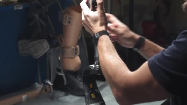 Production of a prosthetic leg. A man creates part of the leg. An engineer is testing the mechanical joint of a prosthetic leg. New sports body part — ストック動画