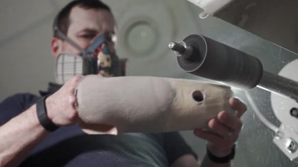 Production of a prosthetic leg. A man creates a part of the leg above the knee. Grinds the plastic part of the leg on a lathe. New body part — ストック動画