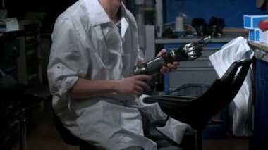 Bir mühendis elektronik biyonik protez kolu test ediyor. Mekanik bir kolun plastik parmaklarını hareket ettiriyor. Protezde modern teknolojiler. Bir bilim adamının elinde sibernetik bir el