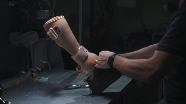 Инженер надевает кроссовки на протезную ногу. Вставляет протез в багажник, завязывает шнурки — стоковое видео