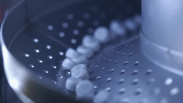 Process of production of pills, tablets. Industrial pharmaceutical concept. Factory equipment and machine. Many pills move on the machine. Medical capsules are sorted by a conveyor belt — Stock Video