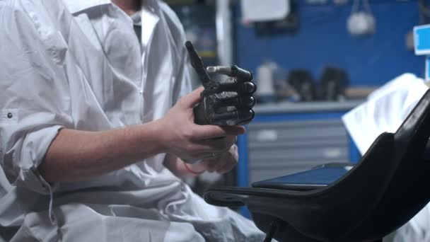 Egy tudós mérnök egy elektronikus bionikus műkart tesztel. Egy mechanikus kar műanyag ujjait mozgatja. Modern technológiák a protézisben. Kibernetikus kéz egy tudós kezében — Stock videók