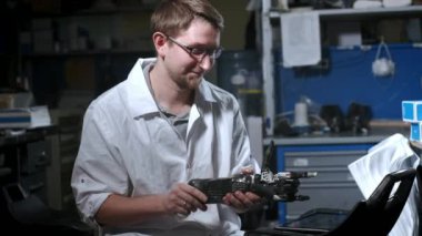 Bir mühendis elektronik biyonik protez kolu test ediyor. Mekanik bir kolun plastik parmaklarını hareket ettiriyor. Protezde modern teknolojiler. Bir bilim adamının elinde sibernetik bir el