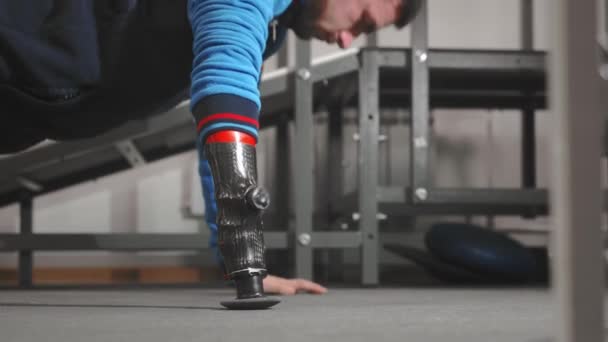 El atleta con un brazo protésico está empujando hacia fuera. Hace ejercicio en el suelo mientras está acostado. Brazo protésico profesional para deportes . — Vídeo de stock