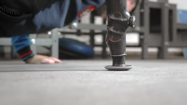 El atleta con un brazo protésico está empujando hacia fuera. Hace ejercicio en el suelo mientras está acostado. Brazo protésico profesional para deportes . — Vídeos de Stock