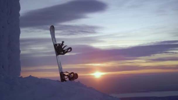 Snowboard is standing in the snow. Stuck in a snowdrift on a sunset background. Snow-covered winter mountains in the north of Russia, Khibiny. Evening landscape beyond the Arctic Circle — Stock Video