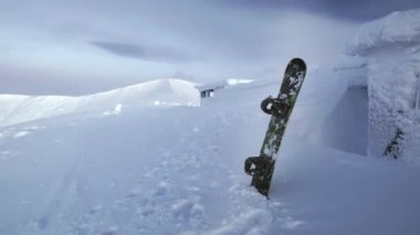 Snowboard karda duruyor. Bir dağ sırasının arka planında kar yığınına sıkışmış. Kuzeyde karla kaplı kış dağları, Khibiny. Kuzey Kutup Dairesi 'nin ötesinde akşam manzarası.