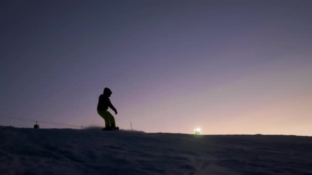 Snowboarder se desliza por la pendiente en una tabla de snowboard. Esquí nocturno — Vídeo de stock