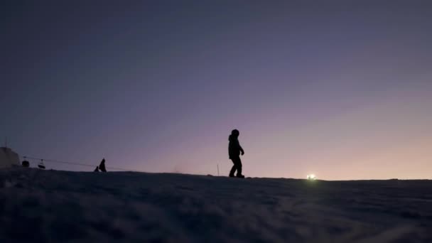 Snowboardos csúszik le a lejtőn egy snowboard. Esti síelés — Stock videók