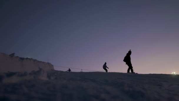 Snowboard sporcusu kayarak yamaçtan aşağı kayıyor. Akşam kayağı. — Stok video