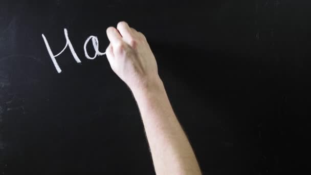 Het woord "gefeliciteerd" geschreven op een zwart schoolbord. Het bord staat op een krijtbord. Mannelijke hand trekt krijt op een schoolbord — Stockvideo