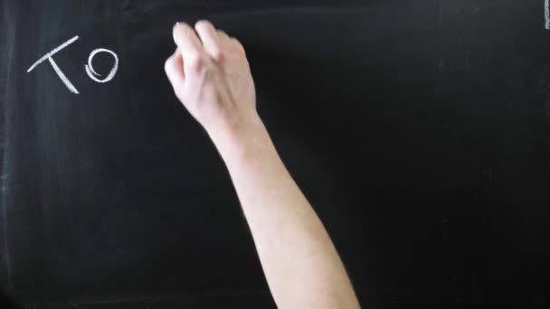 A palavra "continuar" escrita em uma placa preta. O sinal está escrito num quadro de giz. Mão masculina desenha em giz em um quadro negro — Vídeo de Stock