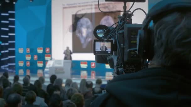 Il cameraman fa video per la televisione. Auditorium, seminario e conferenza sul business.. Videocamera tiene un registro delle prestazioni del docente in sala di presentazione — Video Stock