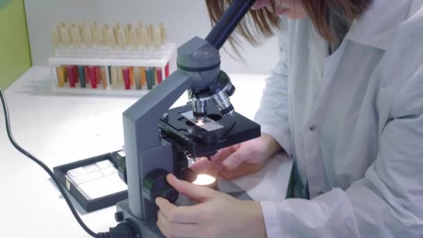 Jeune fille scientifique qui regarde au microscope. Elle étudie les échantillons. Un jeune scientifique mène des recherches scientifiques. Elle fait des recherches sur un virus, cherche un remède pour un vaccin épidémique 