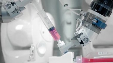 Robotik kol kemoterapi ilacı enjekte ediyor. İki manipülatör ilacı şırıngaya doldurur. Tıpta yeni teknolojiler, yenilikler. Kanser hastalarının ve enfeksiyonluların uzaktan tedavisi.