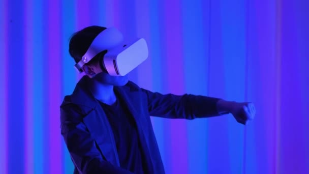 Young guy a professional gamer in virtual reality glasses. Immersed in a parallel reality, creates architectural objects. Futuristic white VR glasses. The designer creates new art. — Stock Video
