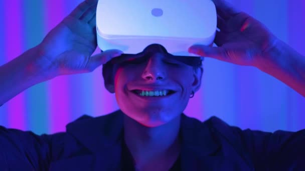 Young guy a professional gamer in virtual reality glasses. Immersed in a parallel reality, creates architectural objects. Futuristic white VR glasses. The designer creates new art. — Stock Video