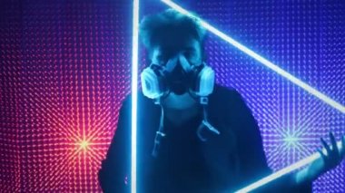 Bir model adam gaz maskesiyle neon bir stüdyoda dans ediyor. Dubstep tarzında kavram. Hava kirliliği ve küresel ısınma. Çılgın parti..
