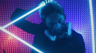 Bir model adam gaz maskesiyle neon bir stüdyoda dans ediyor. Dubstep tarzında kavram. Hava kirliliği ve küresel ısınma. Çılgın parti..