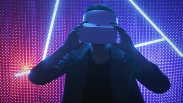 Joven un jugador profesional en gafas de realidad virtual. Sumergido en una realidad paralela, crea objetos arquitectónicos. Gafas de realidad virtual blancas futuristas. El diseñador crea un nuevo arte . — Vídeo de stock