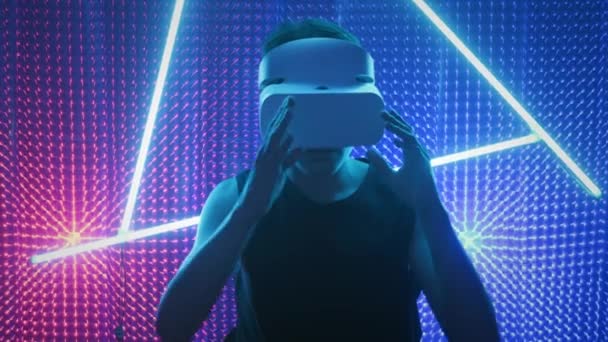 Νεαρός επαγγελματίας παίκτης με γυαλιά εικονικής πραγματικότητας. Βυθισμένο σε μια παράλληλη πραγματικότητα, δημιουργεί αρχιτεκτονικά αντικείμενα. Φουτουριστικό λευκό VR γυαλιά. Ο σχεδιαστής δημιουργεί νέα τέχνη. — Αρχείο Βίντεο