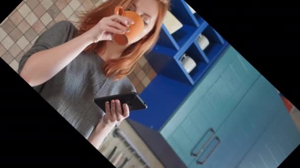 Attraktiv tjej med rött hår dricker morgonkaffe i hemköket. Frilansare morgon. Använder en smartphone, tittar på ett nyhetsflöde eller ett socialt nätverk. Skriver ett meddelande till budbäraren — Stockvideo