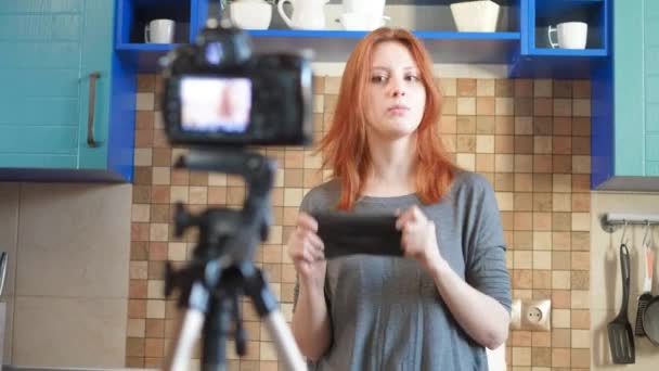 A lány ételblogger egy videót vagy podcastot vesz fel. Megtanítja, hogyan viselj orvosi arcmaszkot. Bloggerek a koronavírus és a világjárvány ellen. A kínai vírus járványa az interneten — Stock videók