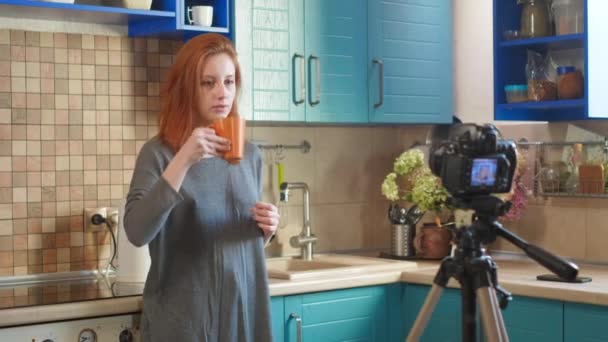 Food blogger girl influenceur enregistre une vidéo ou un podcast dans la cuisine. La femme boit du café du matin dans la cuisine. Une femme communique avec les abonnés, demande à aimer la vidéo . — Video