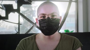 Kel kız kanser hastası. Kadın tıbbi koruyucu siyah bir maske takıyor. Çin koronavirüsüne karşı korur. Kemoterapiden sonra rehabilitasyon. HIV virüsü kapmış. Pandemik sigorta koronavirüsü
