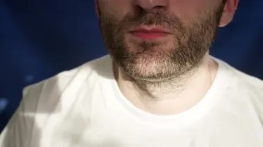 Yakın plan, sakallı bir adam tavuk bacağı yiyor. Tek eliyle nugget tutuyor. Sağlıklı bir hayat sürmüyor, sağlık ve metabolizmayı bozuyor. Yanlış yemek. Kanat ve patates kızartması.