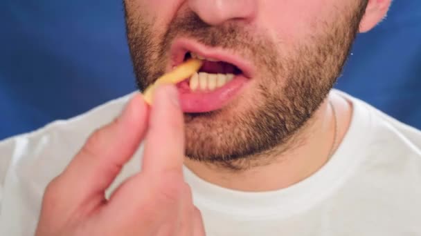 Close-up, a man with stubble eating french fries. It does not lead a healthy lifestyle, impairs health and metabolism. Wrong food