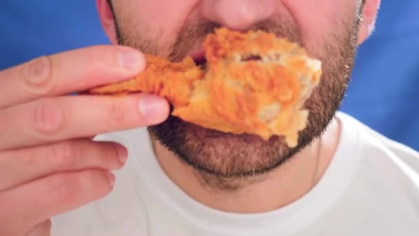 Primer plano, un hombre comiendo comida rápida. Muerde un pedazo de pollo. Tiene pepitas en sus manos. Problemas con una dieta saludable y un estilo de vida pobre. Pollo frito a la plancha. Comida chatarra — Vídeo de stock