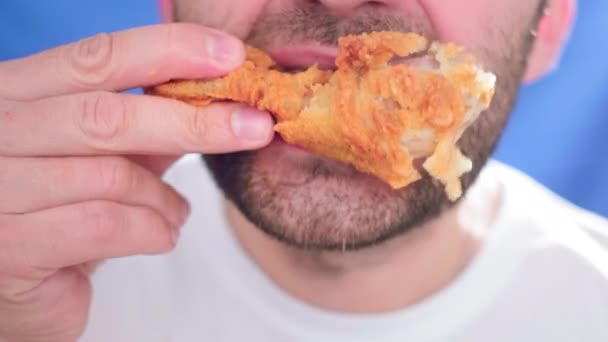 Κοντινό πλάνο, ένας άντρας να τρώει φαστ φουντ. Δαγκώνει ένα κομμάτι κοτόπουλο. Κρατάει ψήγματα στα χέρια του. Προβλήματα με μια υγιεινή διατροφή και κακή ζωή. Ψητό μικρό τηγανητό κοτόπουλο. Βρώμικο φαγητό — Αρχείο Βίντεο