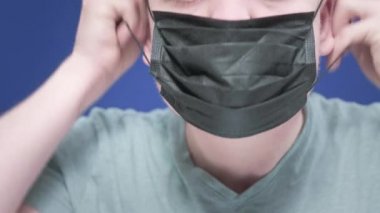 Yüzüne tıbbi maske takan genç bir adamın portresi. Sağlık ve güvenlik hayatı kavramı, N1H1 koronavirüs, virüs koruması, Çin 'de salgın hastalık.
