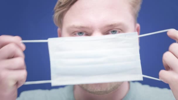 Portret van een jongeman die een medisch masker op zijn gezicht zette. Concept van gezondheid en veiligheid, N1H1 coronavirus, virusbescherming, pandemie in China. — Stockvideo