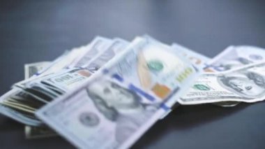 Birçok Amerikan doları yavaşça masaya düşüyor. Adam yeşil Amerikan parası saçıyor. Amerikan finans sistemi