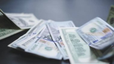Birçok Amerikan doları yavaşça masaya düşüyor. Adam yeşil Amerikan parası saçıyor. Amerikan finans sistemi