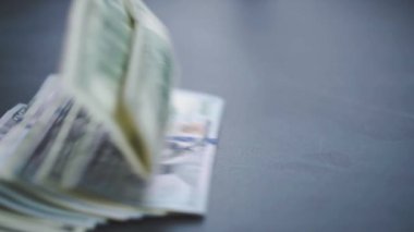 Birçok Amerikan doları yavaşça masaya düşüyor. Adam yeşil Amerikan parası saçıyor. Amerikan finans sistemi