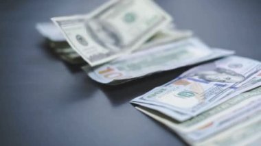 Düşen Dolarlar banknotları. Yüksek kaliteli düşen dolar banknotları. Birçok Amerikan doları yavaşça masaya düşüyor. Adam yeşil Amerikan parası saçıyor. Amerikan finans sistemi